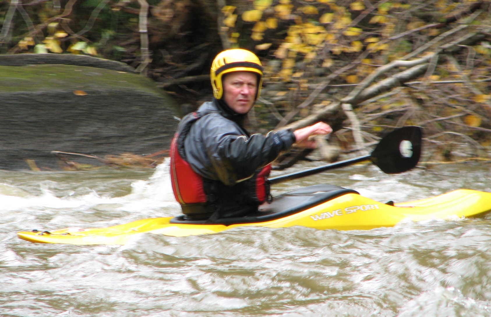 kayaker man paddling a yellow kayak in white water
